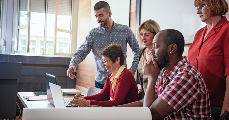 Five educators work together on a computer exercise as they participate in professional development.
