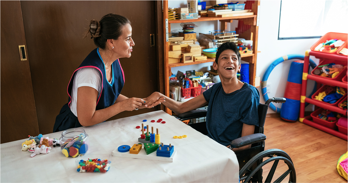 Paraprofessional working in a classroom with a child in a wheelchair